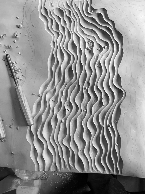 Black and white photo of hand-carving Jesmonite panel for a wall-mounted drinks cabinet.