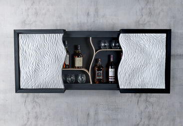 Wall-mounted drinks cabinet in black-stained oak with hand-carved white Jesmonite doors, blending sculptural design with fine woodworking.