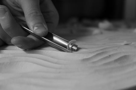 Close-up of hand-carving kelp-inspired organic patterns into PU600 polyurethane model board using rounded gouges, preparing the design for Jesmonite mould-making