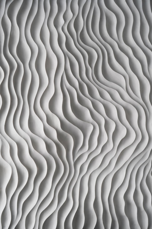 Macro shot of sculptural Jesmonite carving on bespoke drinks cabinet, highlighting intricate texture and shadow play.