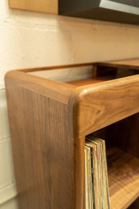 Rounded corner detail of a bespoke HiFi cabinet with vinyl storage in solid walnut