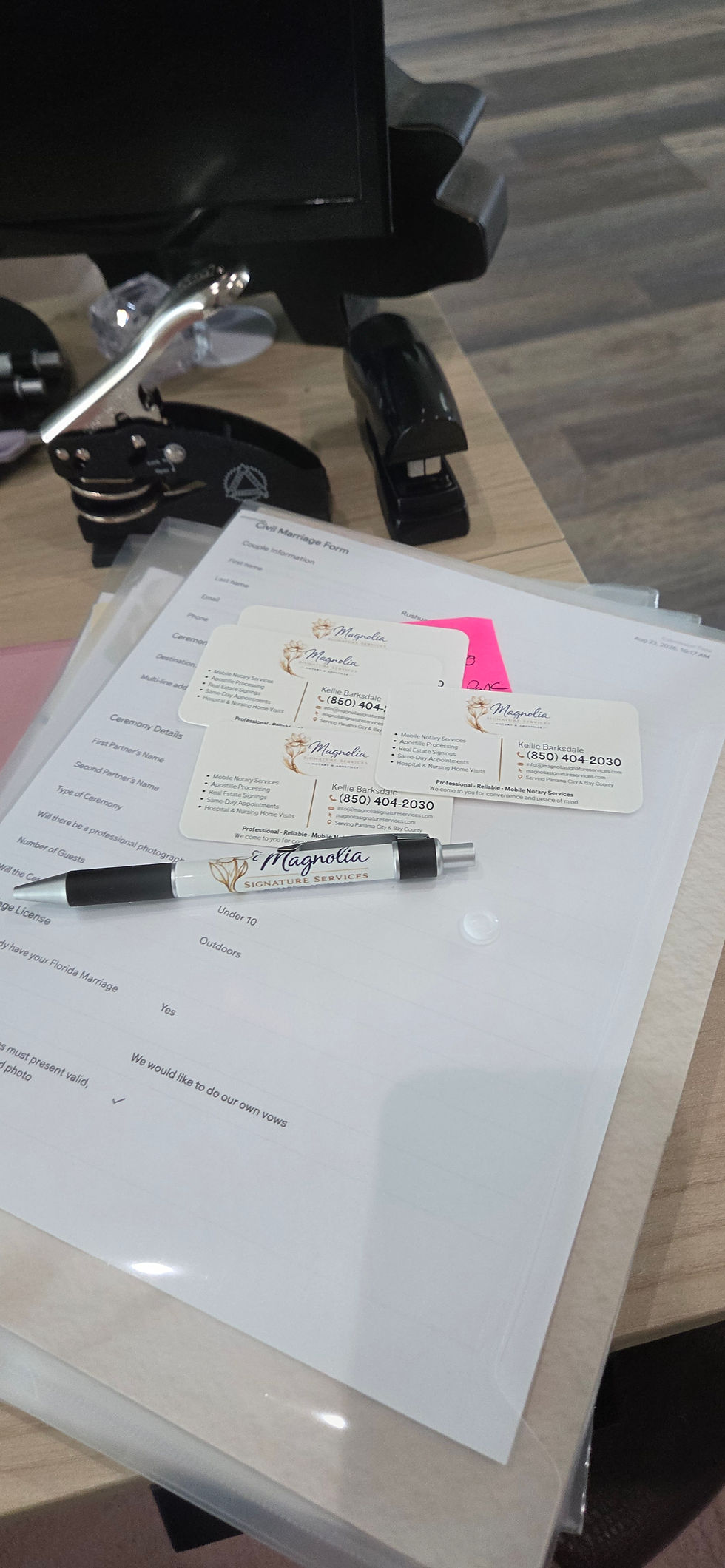 Magnolia Signature Services wedding officiant preparation with marriage ceremony paperwork, branded business cards, and Magnolia Signature Services pen on a desk.