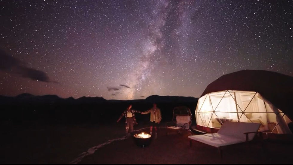Couple under Milkyway beside glamping dome