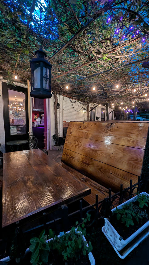 The Wych patio and interior evening time string lights wooden benches and table vine covered patio