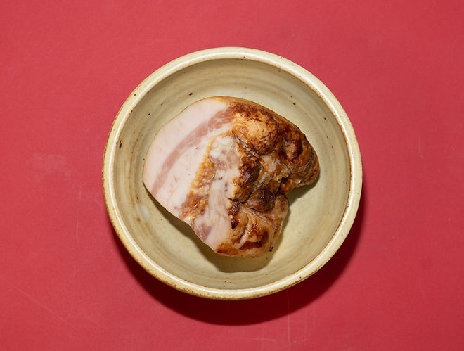 Pasta basta ingredient shot closeup guanciale in earthenware bowl on red surface macro
