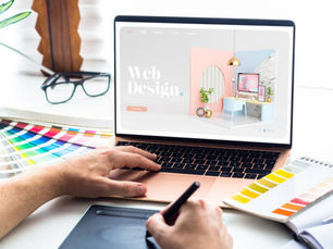 Designer working on a laptop with web design mockup and color swatches on the desk