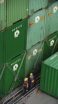 Workers inspect stacked cargo containers