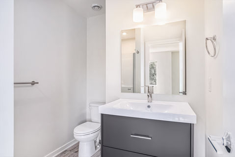 Modern bathroom with sink, mirror, and toilet in a bright setting.