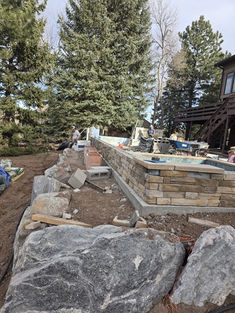 Stacked stone retaining wall under construction in a yard.
