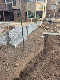 Large stone retaining wall under construction in a yard