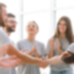 Group of people shaking hands and clapping in a light room