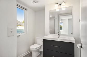 Bathroom with mirror, sink, toilet, and window. 937 Fulton for the modern townhomes.