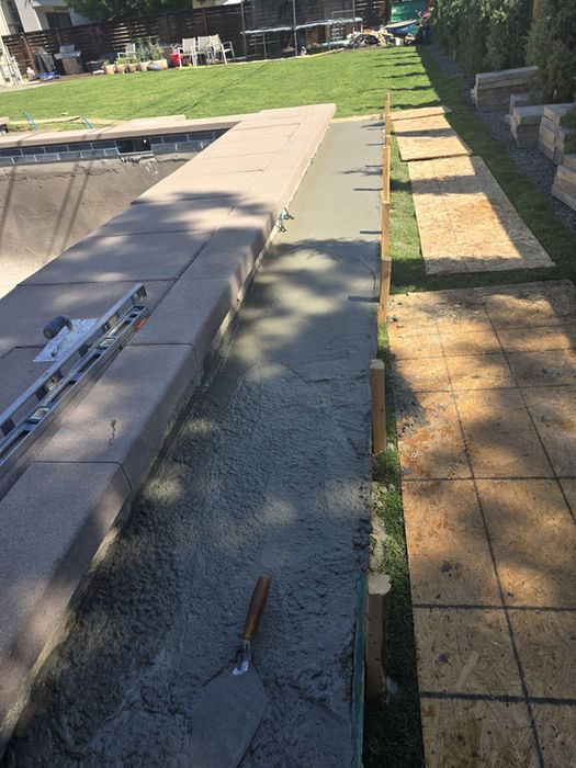 Pool coping installation next to a green lawn