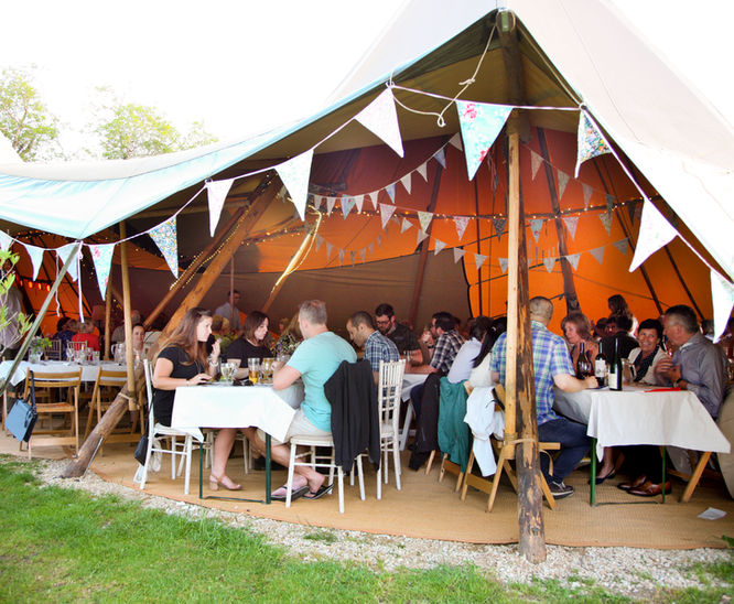 people dining in open sided giant tipis / teepees