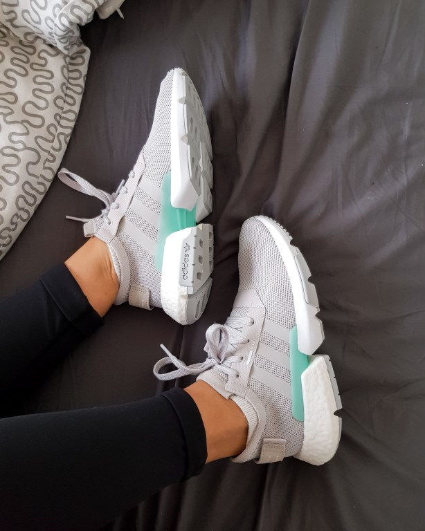 grey and mint green adidas sneakers on bed