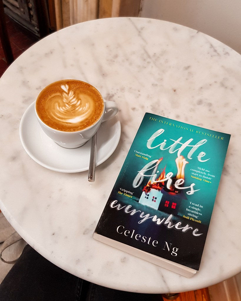 Little Fires Everywhere book by Celeste Ng on marble table with a flat white coffee with latte art - from my summer reading list