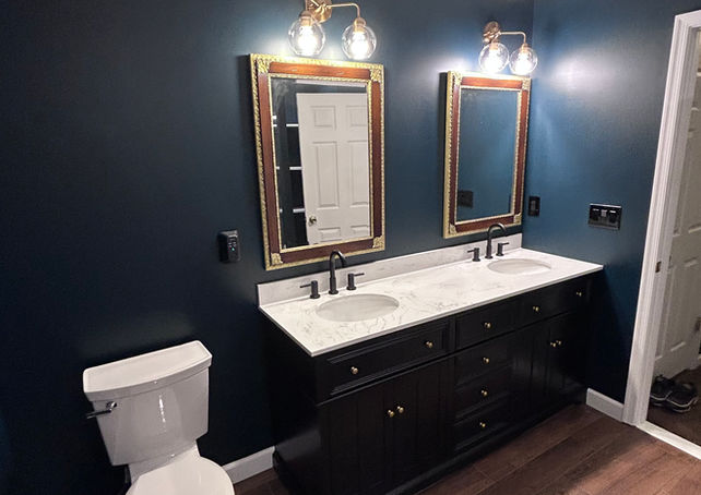 Bathroom vanity with dark paint and ornate golden mirrors