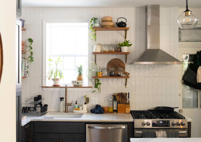Kitchen with floating shelves, stainless hood, dark wood cabinets and white countertop