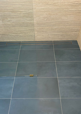 Textured wavy wall tile, with stemless shower with custom drain, blue ceramic flooring