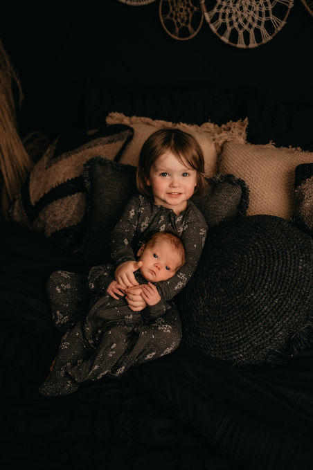 Sibling newborn photos in a dark boho lifestyle room in an Arlington Texas Newborn Studio