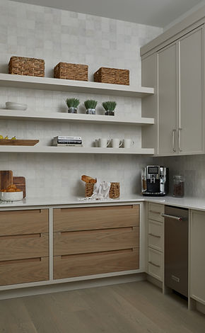 Custom walk-in pantry with white cabinetry, white quartz countertops, floating display shelves, warm oak drawer banks, integrated coffee station, and decorative storage baskets.