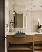 Custom powder room vanity with warm wood cabinetry, black fixtures, and decorative wall detailing.