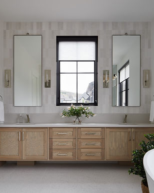 Bright transitional bathroom with a light oak vanity, integrated white countertop, brushed nickel hardware, vertical white tile backsplash, and large black-framed window providing natural light.