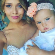 Beautiful bride with professional makeup holding her baby with a flower headband