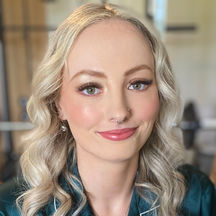 woman with curls in blonde hair and glam makeup smiling at camera