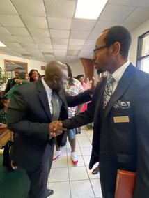Pastor Thompson greeting shaking hands with W. Turner in church lobby
