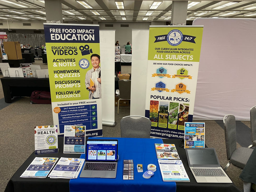Tables with laptops and brochures are set up at an educational event. Banners promote free food impact education, highlighting health and environment.