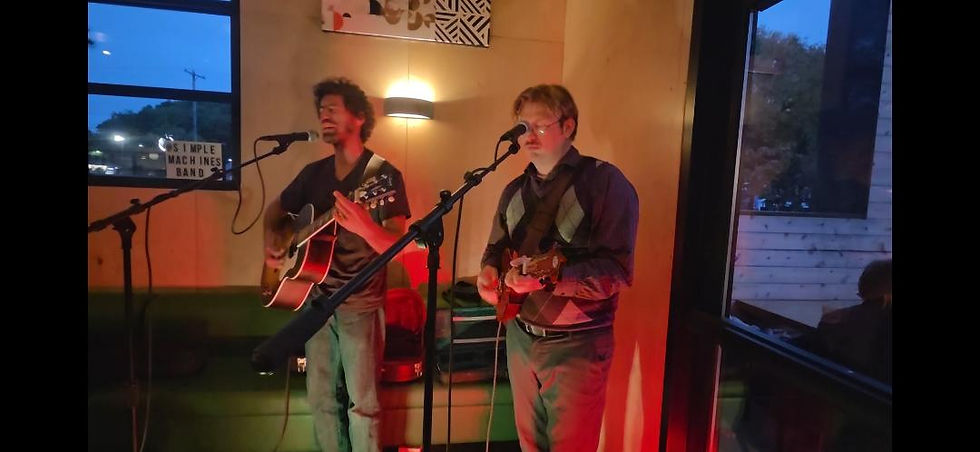 Max on guitar and John on mandolin sing at microphones during a Simple Machines show.