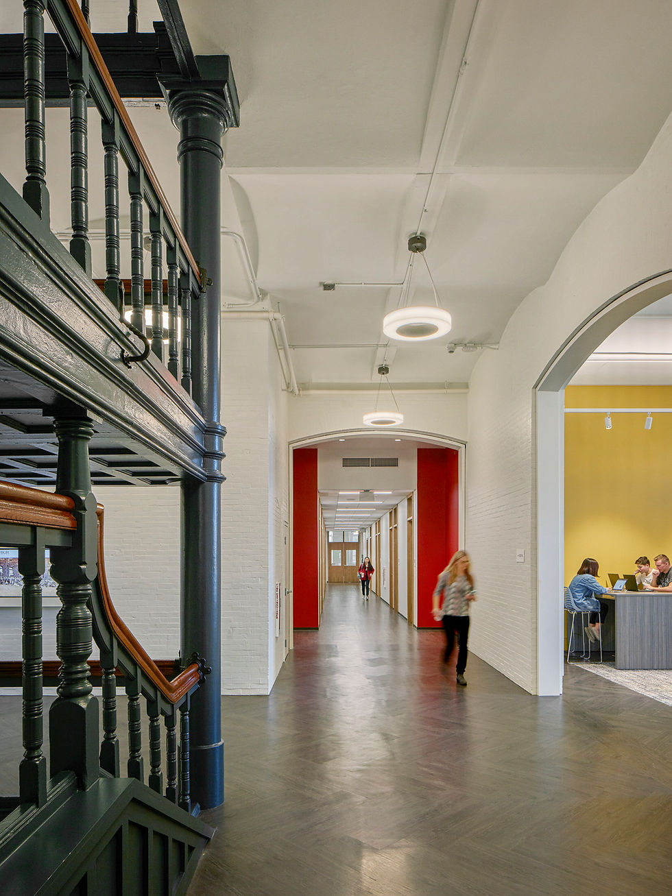 Renovated historic corridor featuring arched ceilings, restored wood detailing, and bright modern finishes with students walk