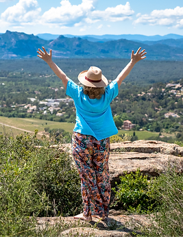 A woman raising her arms and facing a beautiful view