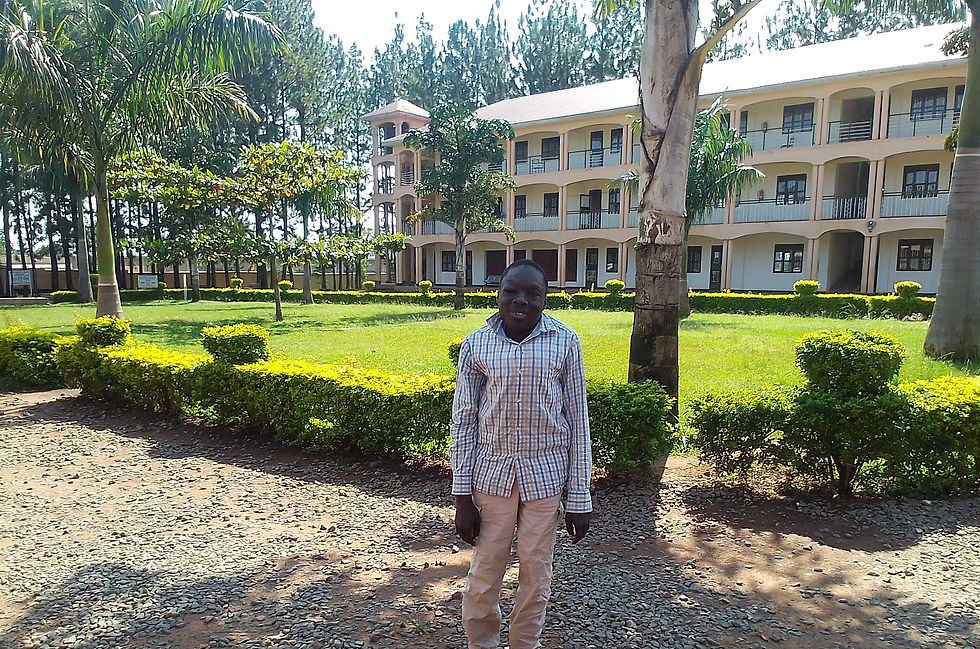 Oryem standing in front of green grass and tropical trees with a university in the background