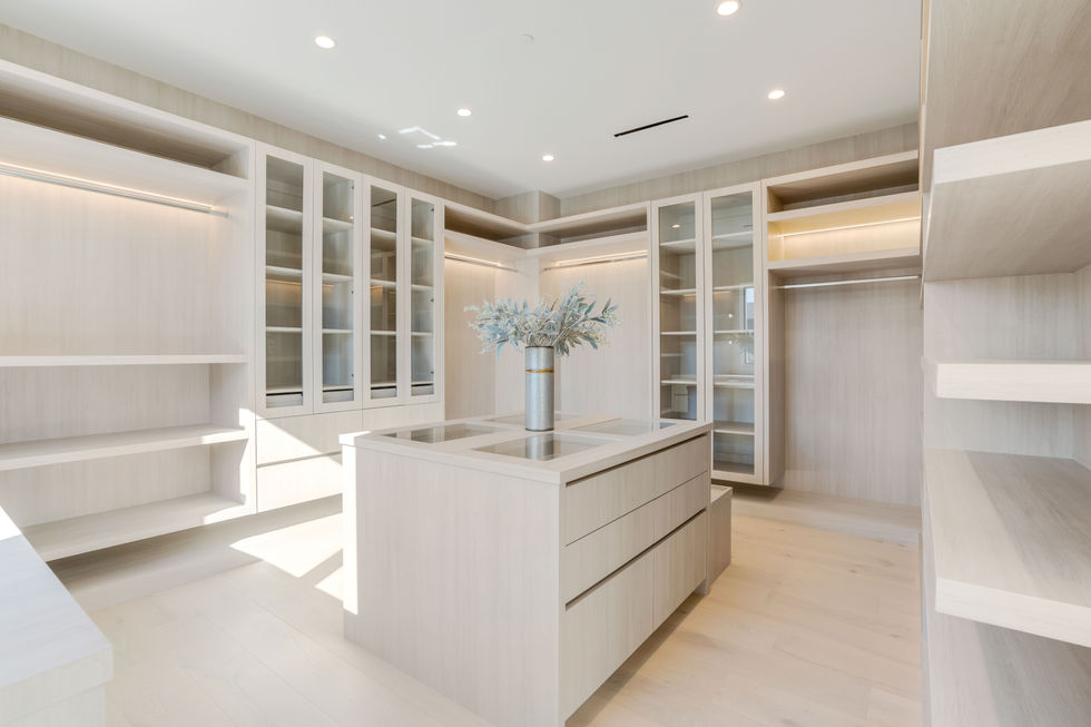 Custom luxury walk-in closet in Los Angeles new construction home featuring built-in shelving, modern cabinetry, and minimalist design.