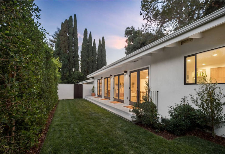 Modern Los Angeles home exterior at twilight with glass doors and landscaped backyard.