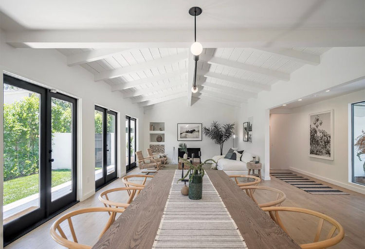 Modern living and dining area in Los Angeles with vaulted ceiling, exposed beams, and large glass doors.