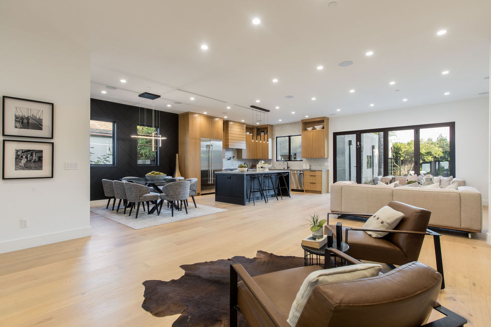 Modern open-concept living and dining area in Los Angeles with custom kitchen, glass dining table, and luxury finishes.