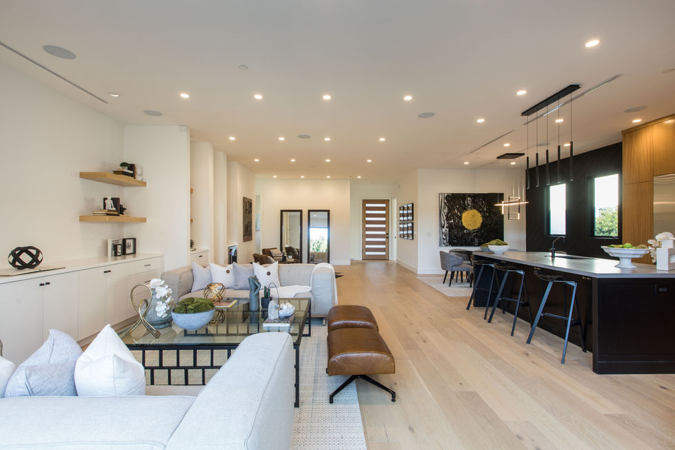 Modern open-concept living and dining area in Los Angeles with custom kitchen, glass dining table, and luxury finishes.