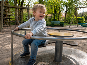 Junge sitzt auf einem Karussell auf einem Spielplatz