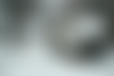 An RV (Recreational Vehicle) with snow on top of the roof in a snowy landscape with a welcome sign.