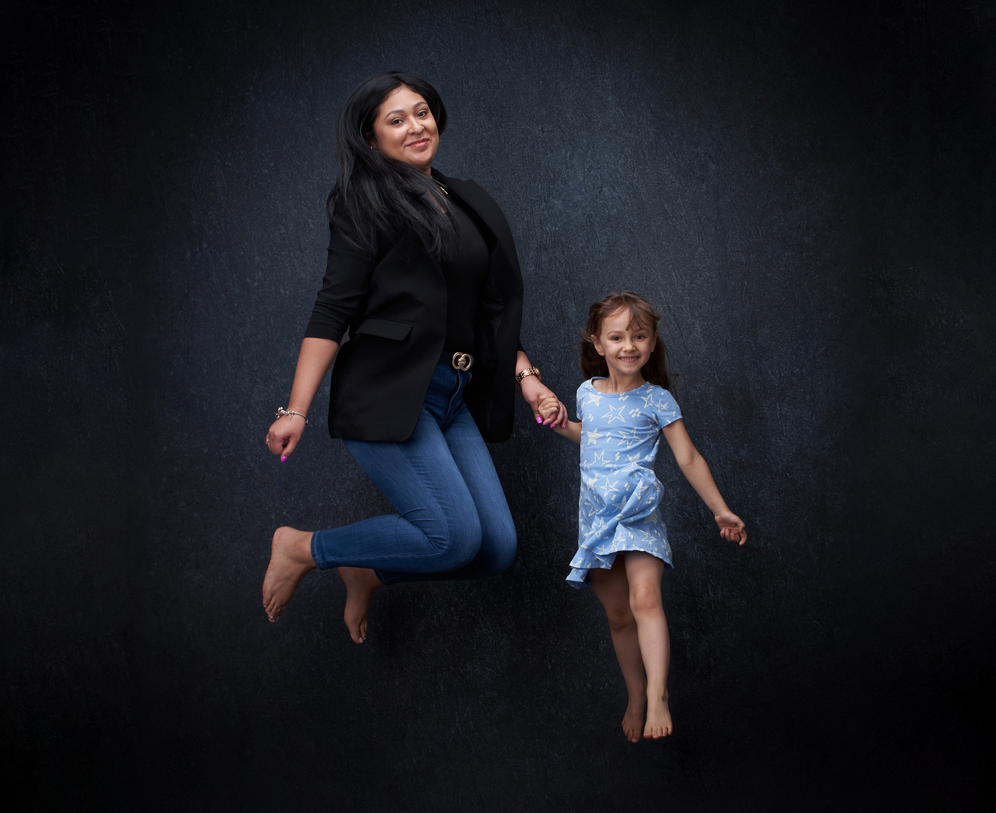 Mère et jeune fille photographiées en mouvement lors d’une séance famille en studio.