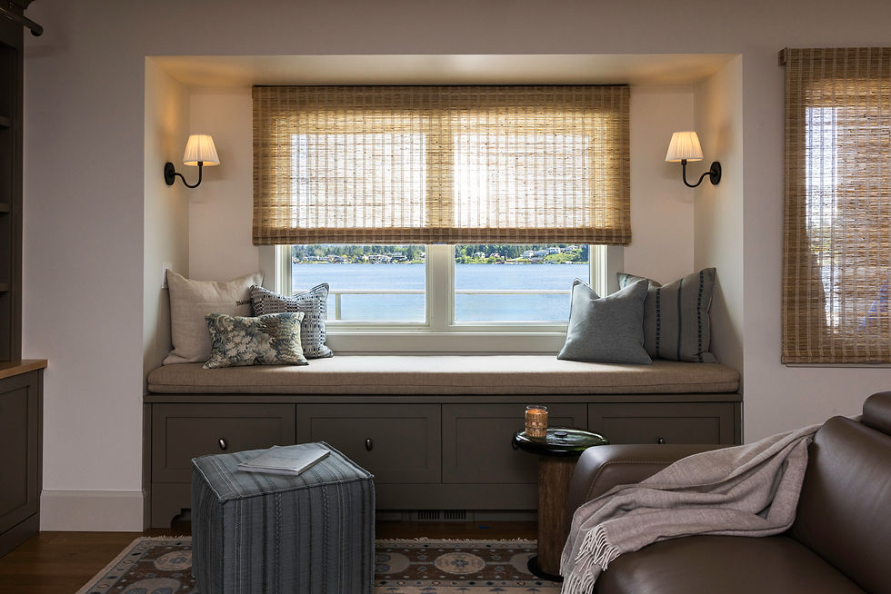 Built-in window seat with a lake view, blue pillows, woven shades, and wall sconces