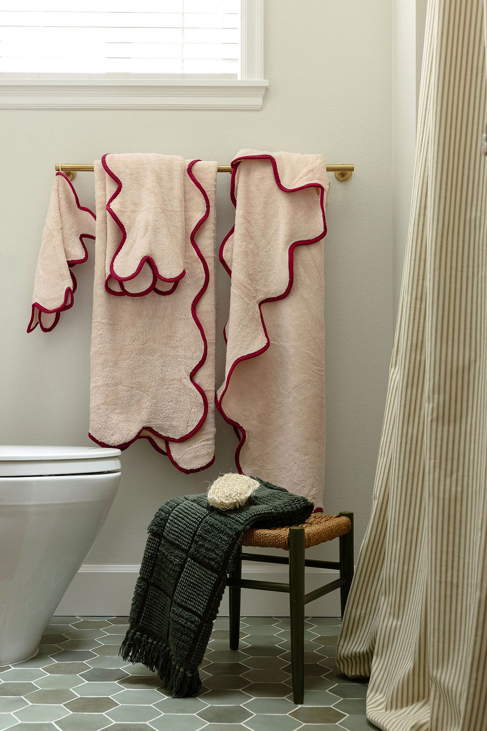 Pink abstract artwork and a black accent chair in a neutral bathroom