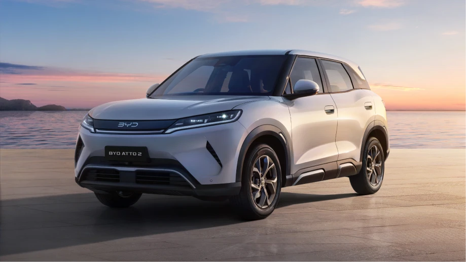 White BYD electric SUV on a beach at sunset