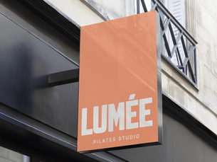 Außenbeschilderung des Lumée Pilates Studios mit modernem, klaren Logo-Design in warmem Orangeton – minimalistisches Branddesign von ISSO Design Salzburg.