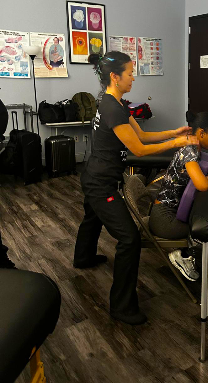 me practicing a chair massage on another student in the classroom