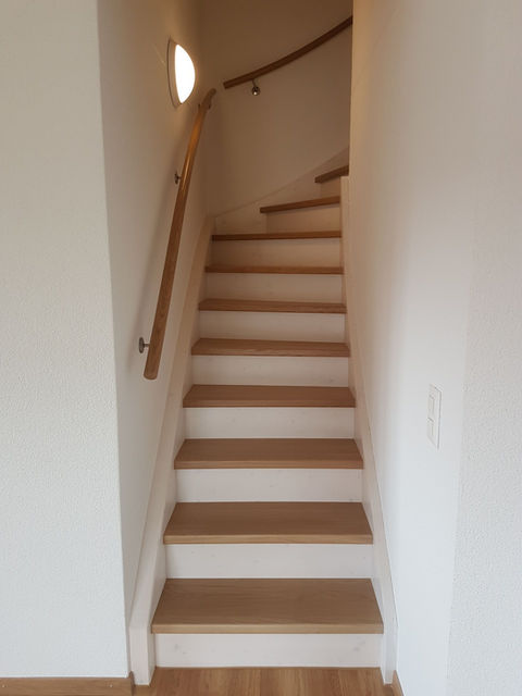 Treppe aus Eichenholz zwischen zwei weissen Mauern