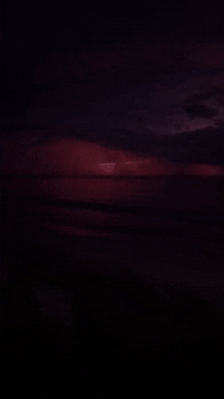 Lightning storm over a red sunset on a b